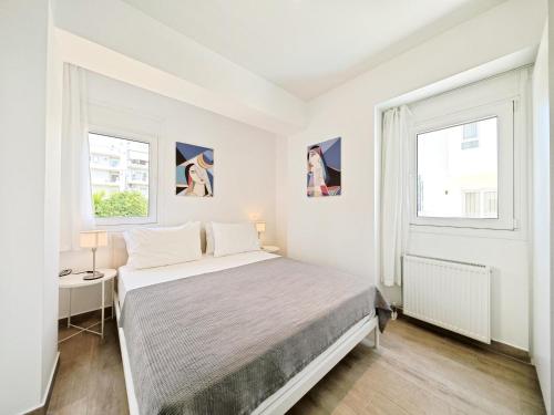 a white bedroom with a bed and two windows at Marathonomachon by Verde Apartments in Athens