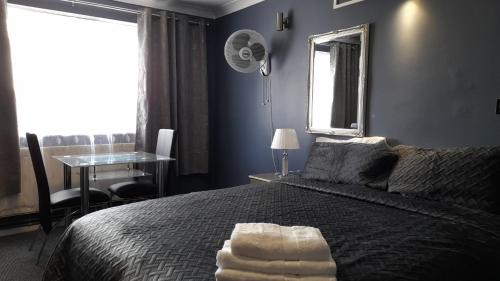 a bedroom with a bed and a table and a window at Osterley Park Group Ltd Osterley Park Hotel in Isleworth