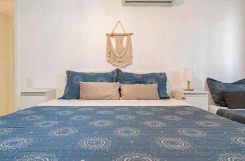 een bed met een blauw dekbed en kussens bij Apartamentos de 2 quartos com piscina na Praia dos Anjos in Arraial do Cabo