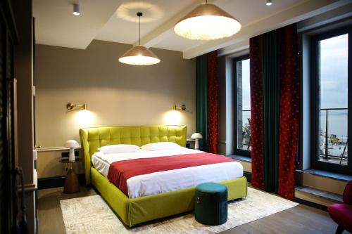 a bedroom with a bed with a yellow headboard and windows at Hotel Retro in Batumi