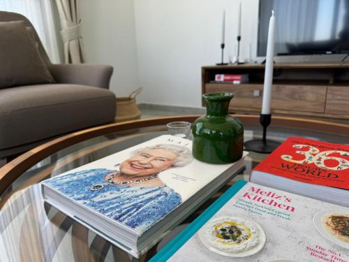 a glass coffee table with a magazine and a vase at Penthouse in Lapta, a Cozy Coastal Retreat in Lapithos