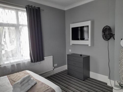 a bedroom with a bed and a tv on the wall at Osterley Park Group Ltd Osterley Park Hotel in Isleworth