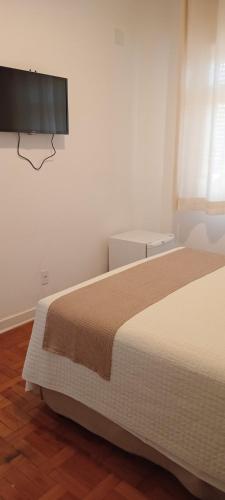 a bedroom with a bed and a flat screen tv at Grande Hotel Amparo in Amparo