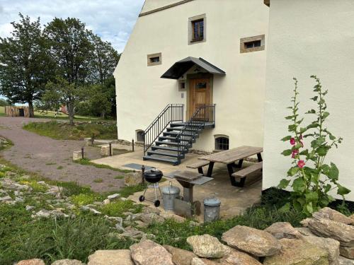 a building with a staircase and a bench and a grill at Lindenhof Michaelis - Urlaub auf dem historischen Gutshof in Liebstadt