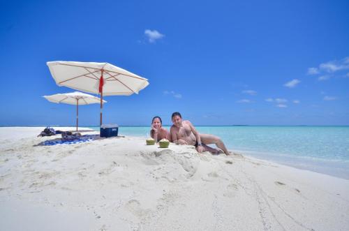 two people sitting in the sand on the beach at Ganduvaru Villa in Ukulhas