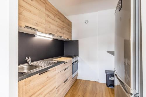une cuisine avec des armoires en bois et un évier dans l'établissement T1 Confort Tête d'Or Doua - Parking Gratuit, à Villeurbanne