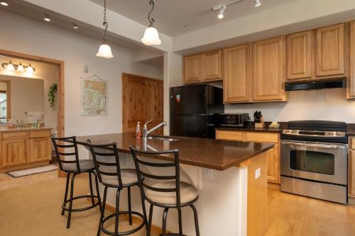 a kitchen with wooden cabinets and a island with bar stools at Trailhead Lodges 821 in Winter Park