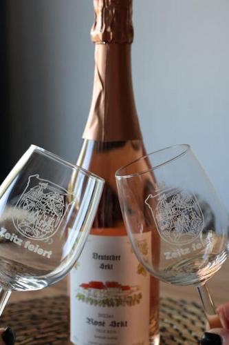 two wine glasses sitting next to a bottle of wine at Weingut Lahmer August Appartment Rebstock in Kretzschau