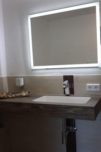 a bathroom with a white sink and a mirror at Weingut Lahmer August Appartment Rebstock in Kretzschau