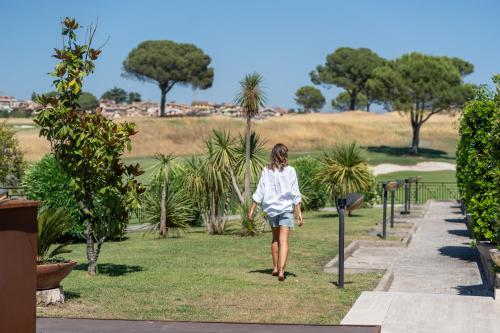 a woman walking down a path in a park at Carpediem Roma Golf Club in Marco Simone