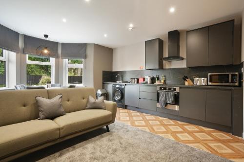 a living room with a couch and a kitchen at The Olive Tree Aparthotel in Hull