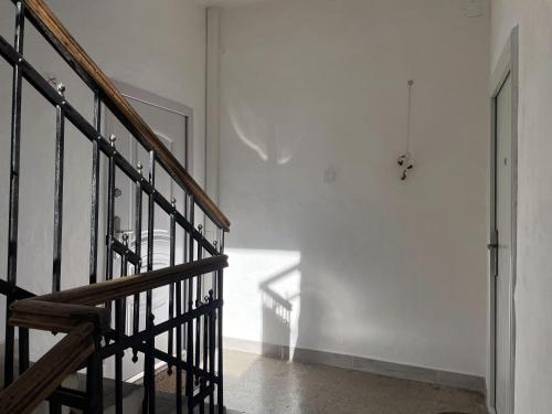 a stairway with a wooden railing and a white wall at Fészek Apartmanház in Tapolca