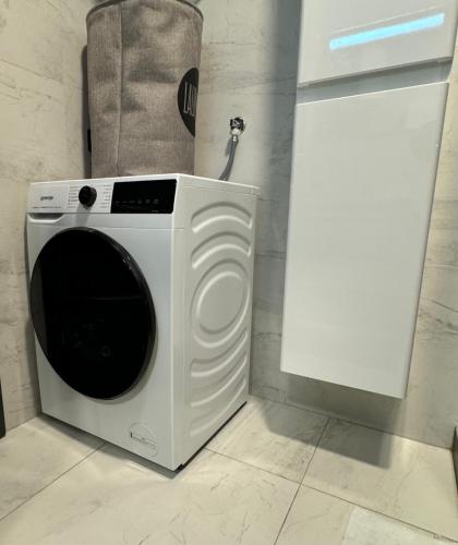 a white washing machine in a kitchen with a cabinet at Penthouse Apartman Bulevar Sarajevo in Sarajevo