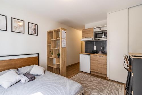 une petite chambre avec un lit et une cuisine dans l'établissement Studio Charpennes - Parking privé gratuit, à Villeurbanne