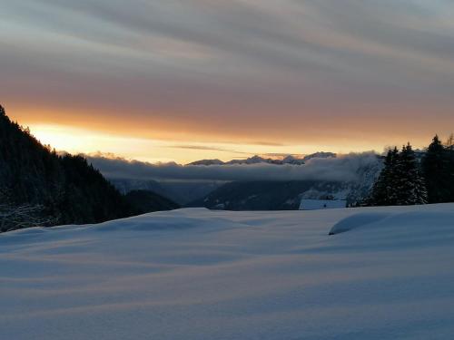a view of a snow covered mountain with the sun setting at B&B Sass de Mura in Fiera di Primiero