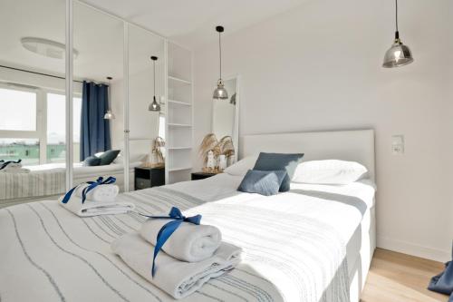 a white bedroom with two beds with towels on them at Casa Baia BlueApart Hel in Hel