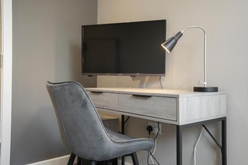 a computer desk with a monitor and a chair at The Olive Tree Aparthotel in Hull