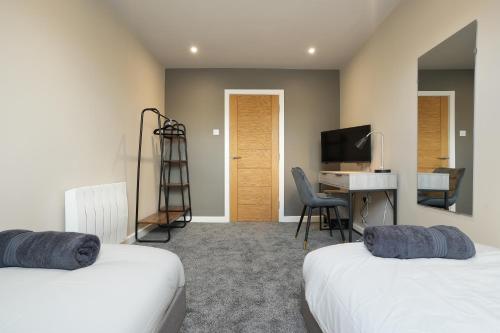 a room with two beds and a desk and a television at The Olive Tree Aparthotel in Hull