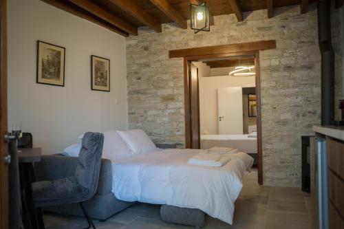 a bedroom with a bed and a chair and a bathroom at AROMA DRYOS in Kato Drys