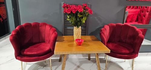a table with two red chairs and a vase of flowers at IMPERIAL ROOMS - ULTRACENTRAL - jacuzzi cu hidromasaj in Oradea