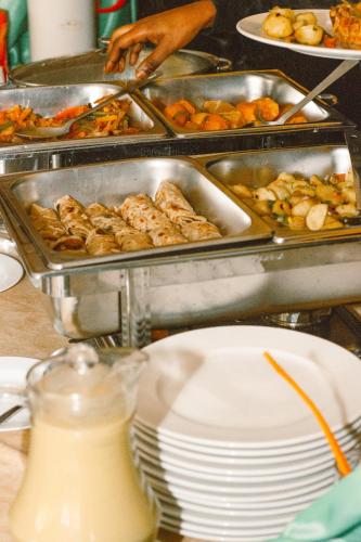 a buffet with trays of food and plates of food at LUSHOTO EXECUTIVE LODGE in Lushoto