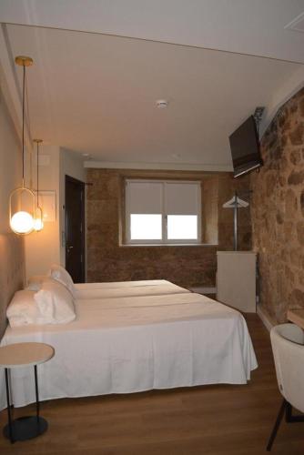 a bedroom with a large white bed and a tv at Corona de Galicia Rooms in Padrón