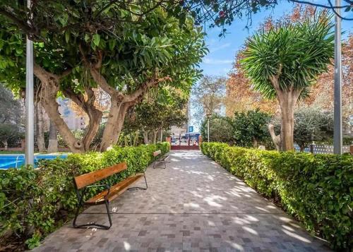 a walkway with benches and trees in a park at Luxury Family Levante Beach in Benidorm
