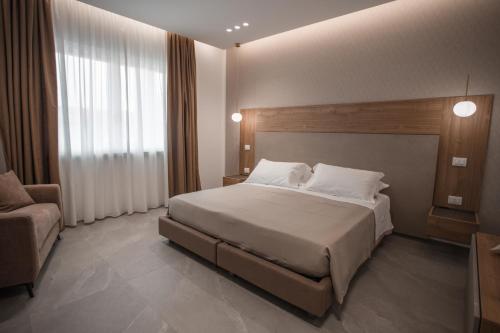 a bedroom with a large bed and a chair at Alexander House Hotel in San Ferdinando