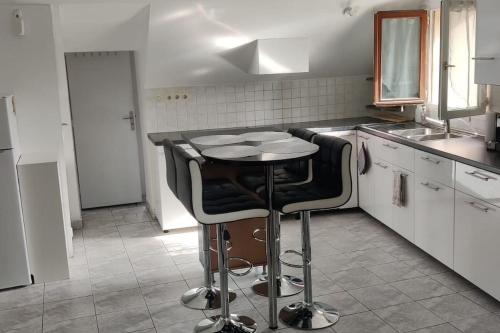 une cuisine avec une table et deux tabourets de bar dans l'établissement Location appartement pour les JO, à Villeparisis