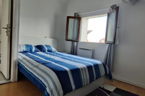 - une chambre avec un lit bleu et blanc et une fenêtre dans l'établissement Location appartement pour les JO, à Villeparisis