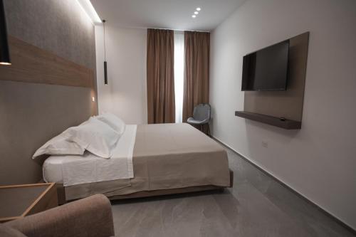 a hotel room with a bed and a flat screen tv at Alexander House Hotel in San Ferdinando