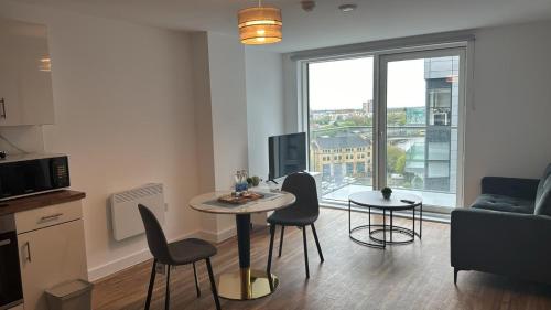 a living room with a table and chairs and a window at Penthouse height Flat, City View Balcony, Quiet, Free Wifi, Gym & More Minimalistic Home in Manchester