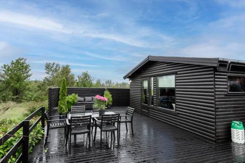 a black cabin with a table and chairs on a deck at Modern Summerhouse Views Outdoor Spaces Patio in Miðdalur