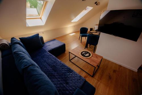a living room with a blue couch and a television at Loft apart Pluzine in Pluzine