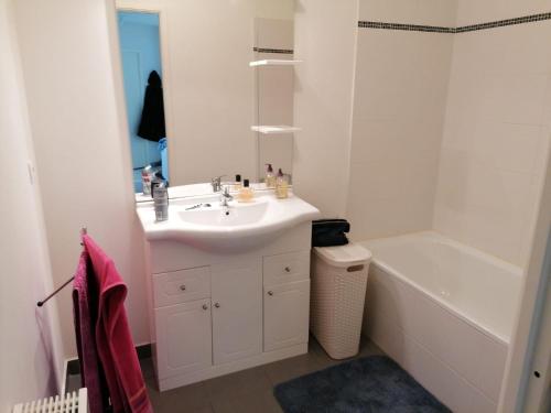 La salle de bains blanche est pourvue d'un lavabo et d'une baignoire. dans l'établissement La Cigale, à Bagnols-en-Forêt