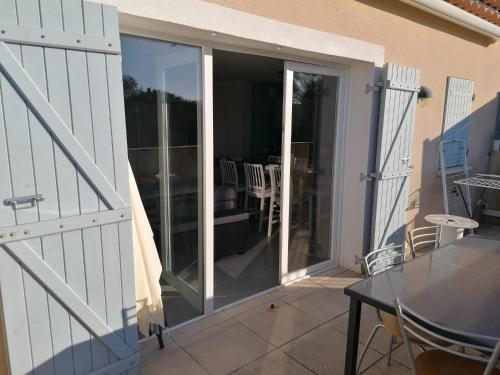 une porte coulissante en verre avec une table sur un patio dans l'établissement La Cigale, à Bagnols-en-Forêt