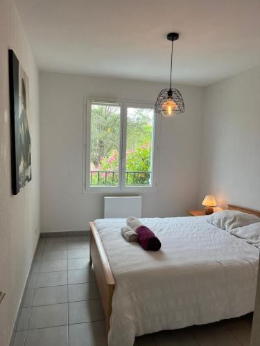 une chambre blanche avec un lit et une fenêtre dans l'établissement La Cigale, à Bagnols-en-Forêt