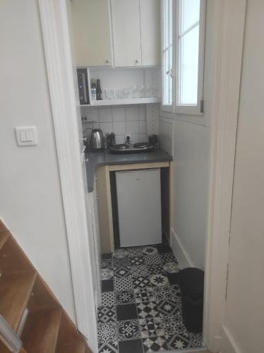 Elle comprend une petite cuisine avec un évier et un sol noir et blanc. dans l'établissement Appartement centre-ville - Kids Friendly, à Clichy