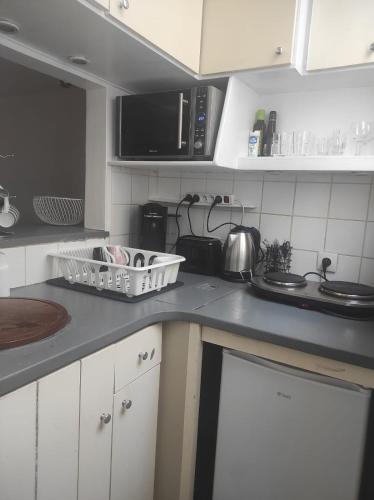 une cuisine avec des armoires blanches et un comptoir dans l'établissement Appartement centre-ville - Kids Friendly, à Clichy
