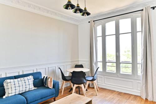 un salon avec un canapé bleu et des chaises dans l'établissement Appartement lumineux - Puteaux - II, à Puteaux
