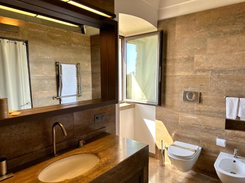 a bathroom with a sink and a toilet and a mirror at Relais Histò San Pietro Sul Mar Piccolo in Taranto