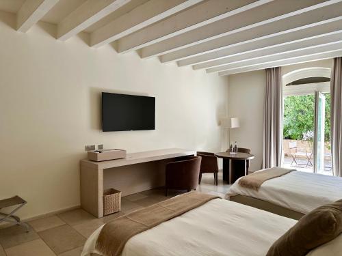 a bedroom with two beds and a desk with a television at Relais Histò San Pietro Sul Mar Piccolo in Taranto