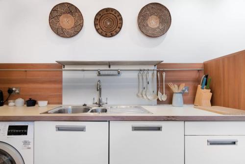 a kitchen with a sink and plates on the wall at Super Central - Georgian Double Upper Flat with Castle Views in New Town in Edinburgh