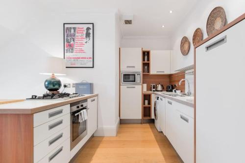 a kitchen with white cabinets and white appliances at Super Central - Georgian Double Upper Flat with Castle Views in New Town in Edinburgh