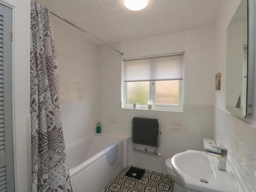 a white bathroom with a tub and a sink at Castelian in Bridlington