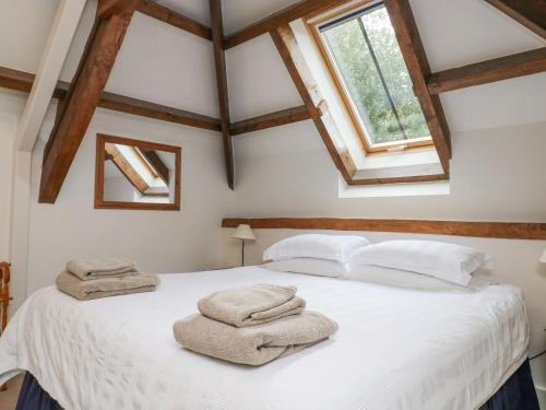 ein Schlafzimmer mit einem weißen Bett mit Handtüchern darauf in der Unterkunft Ixworth Cottage in Ottery Saint Mary