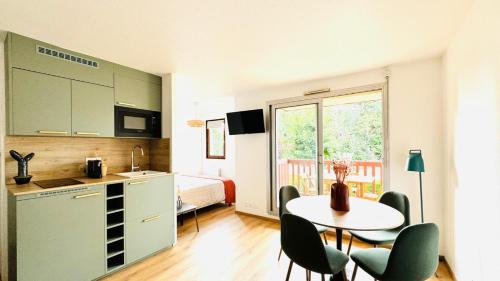 Cette chambre comprend une cuisine, une table et un lit. dans l'établissement My Appartement Plage des Ammonites - Deauville, à Tourgéville