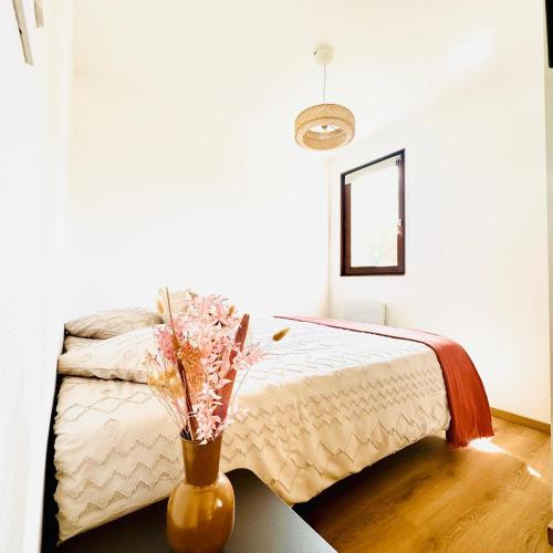 - une chambre avec un lit et un vase avec des fleurs dans l'établissement My Appartement Plage des Ammonites - Deauville, à Tourgéville