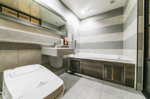 a bathroom with a toilet and a sink and a tub at Bellino Hotel in Osan