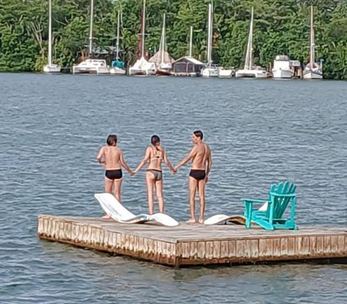 three people in bathing suits standing on a dock in the water at Tortugal Boutique River Lodge in Rio Dulce